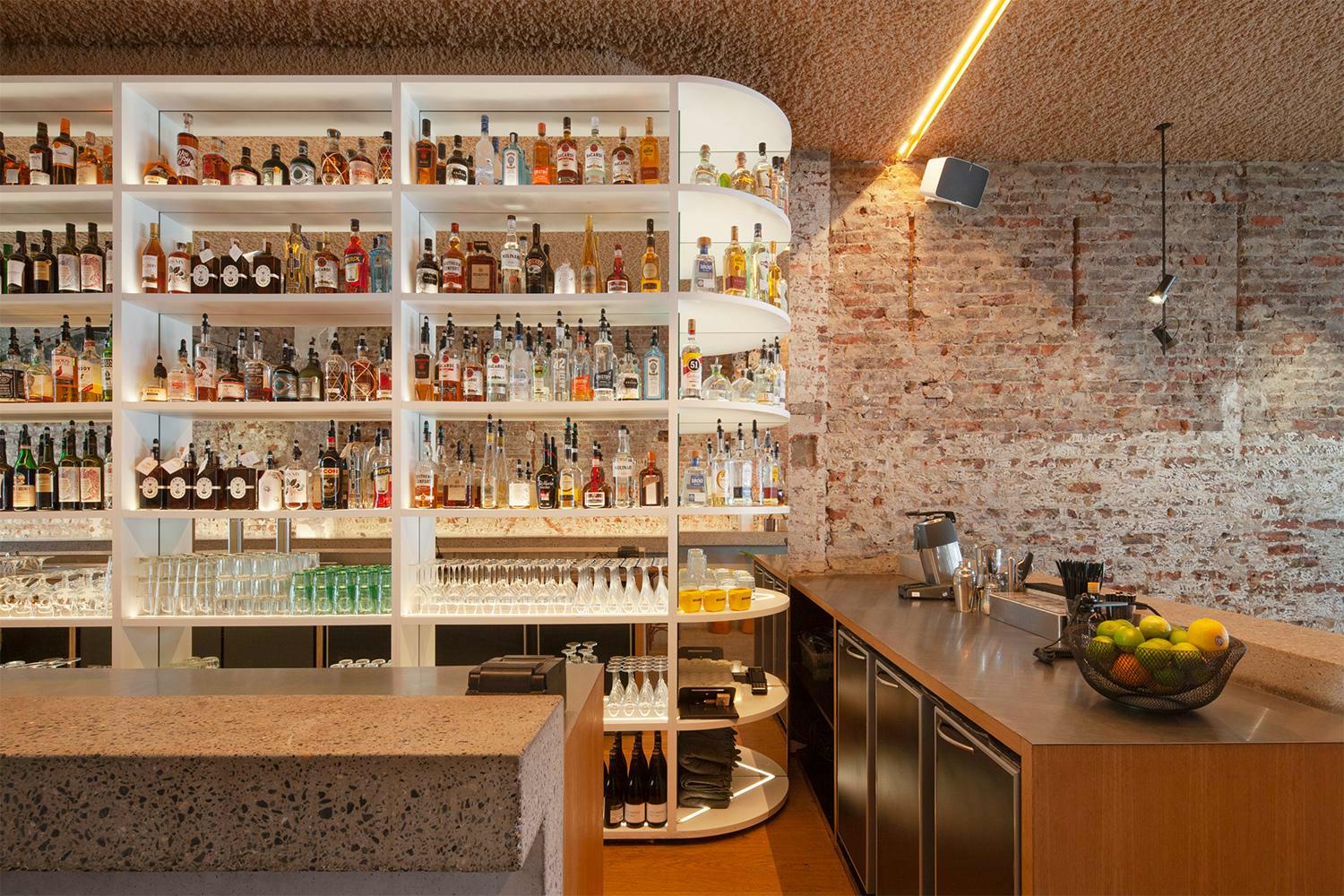Bar met sterke drank en glazen op schappen in bar Eltòn in Gent